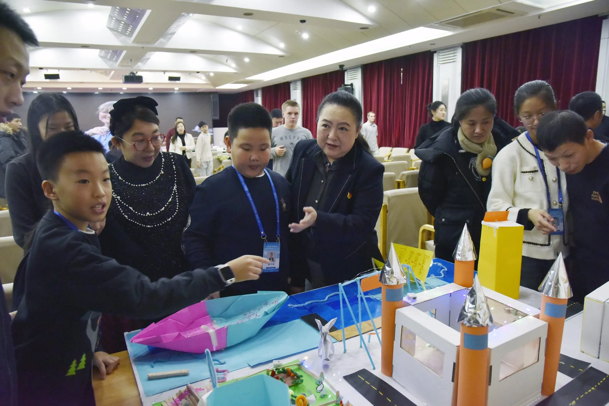 A student explaining a project model to teachers and parents